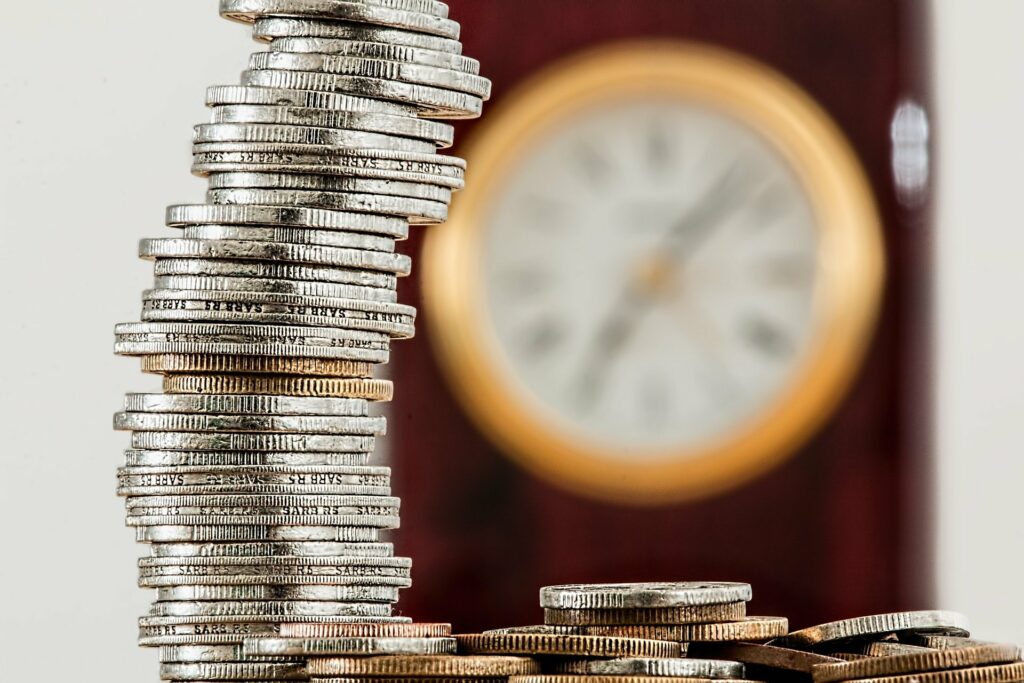 A column of coins in the background with a clock
