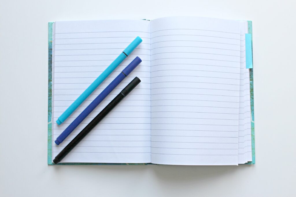 Three markers on an open notebook